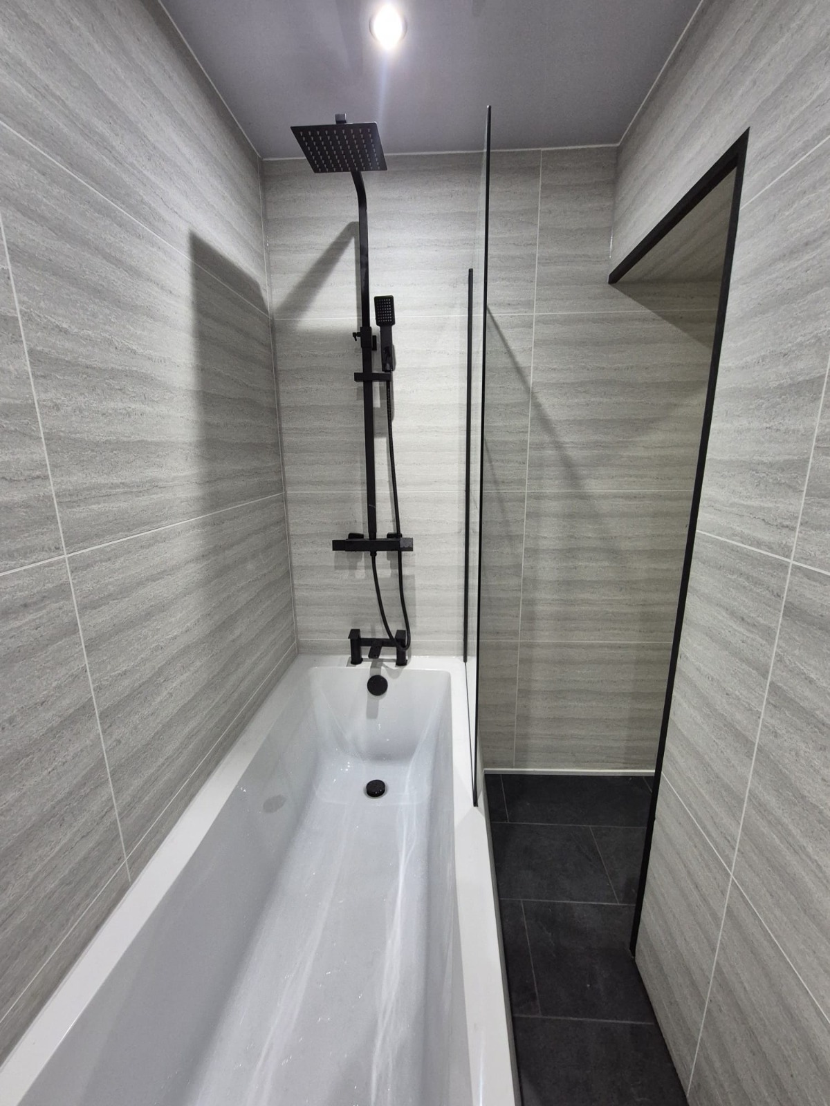 Stone-grey tiled bathroom with matte black fixtures
